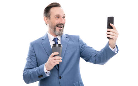 happy man blogger in suit meking selfie on phone and drink coffee isolated on white, video call.の写真素材