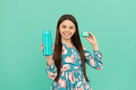 kid with shower gel and face cream. happy girl hold shampoo. child with hair mask conditionerの写真素材