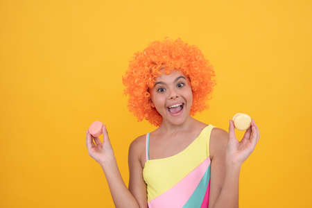 macaroon cookie. happy childhood. birthday party. funny kid in clown wig hold french macaron.の写真素材
