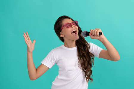 Happy kid singer sing karaoke song to microphone blue background, musicの写真素材