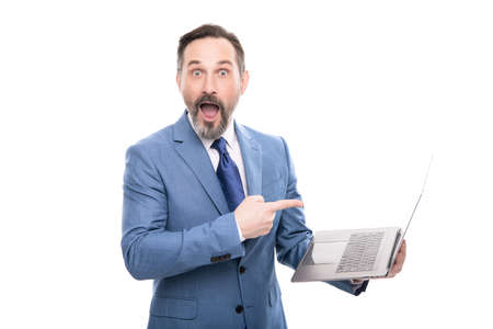 amazed boss pointing finger on modern wireless laptop. mature businessman working onlineの写真素材