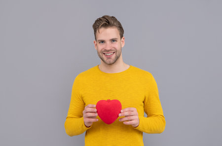 My heart for you. Handsome guy smile holding red heart. Happy Valentines dayの写真素材