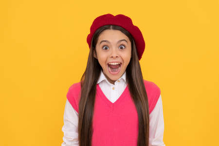 surprised teen school girl in french beret on yellow background, happinessの写真素材