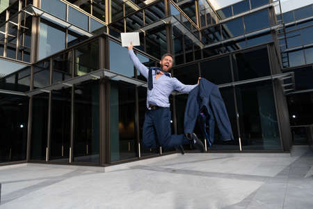 successful happy businessman man jumping with laptop celebrating business success outdoor, successの写真素材