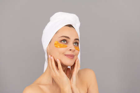 Definig beauty. young woman in terry towel use patch. beauty day in spa.の写真素材