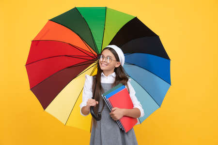 kid in beret with rainbow umbrella. autumn season. rainy weather forecast. back to school.の写真素材