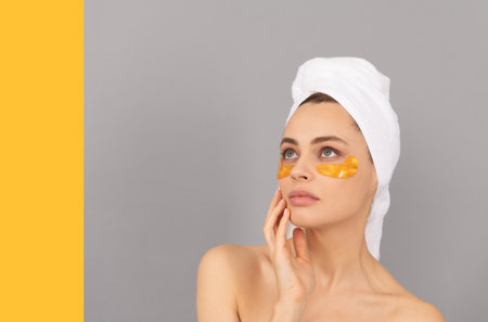 beautiful girl with terry towel use facial golden eye patch for skin, copy space, beautyの写真素材