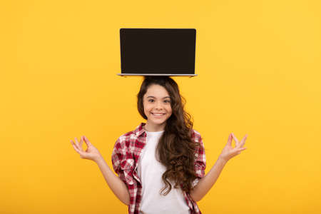 happy smart teen girl meditating with laptop on head presenting school online lesson, estudyの写真素材