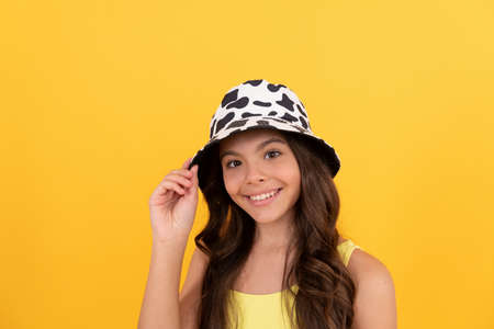happy child in summer bucket hat has curly hair on yellow background, beach fashionの写真素材