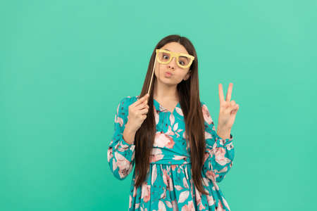 Stay cool. Cool girl hold booth glasses showing victory hand. Enjoying disguise partyの写真素材
