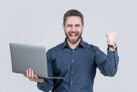 happy handsome mature man businessman with beard working online on laptop, success in business