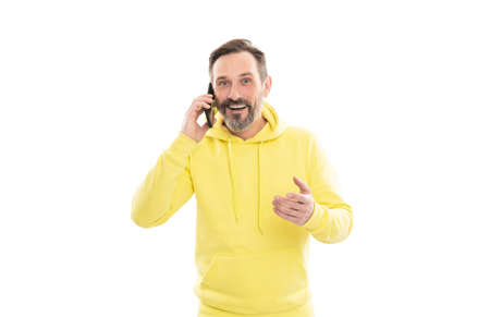 smiling handsome mature man in hoody speaking on phone isolated on white, conversation.の写真素材