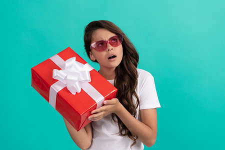 fashionable curious kid in sunglasses hold gift box, curiosityの写真素材