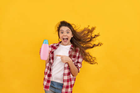 happy teen girl with long curly hair hold shampoo bottle, hairdresserの写真素材