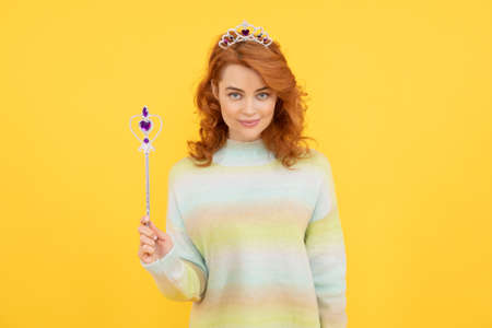 smiling redhead woman in queen crown with magic wand, wishの写真素材