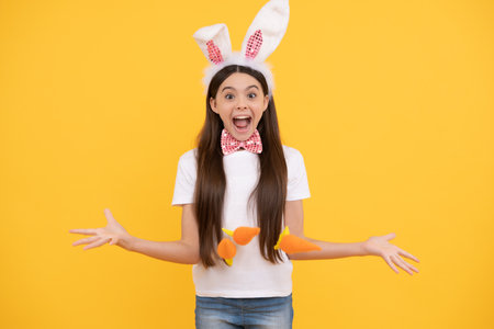 surprised easter teen girl in bunny ears and bow tie hold carrot, easter