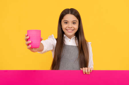 Happy tween girl give plastic cup with drink holding advertising board for copy space, beverageの写真素材