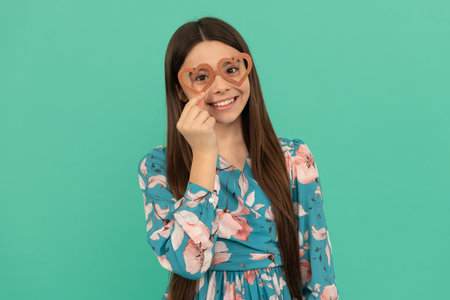 Happy tween girl smile wearing heart-shaped prop glasses for Valentines day party, February 14の写真素材