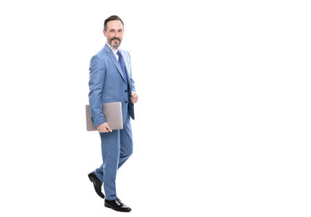 happy grizzled boss in suit full length walking with laptop isolated on white copy space, freelancerの写真素材