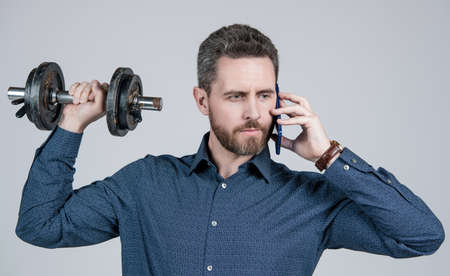 communication. handsome businessman with dumbbell speak on phone. digital sport.の写真素材
