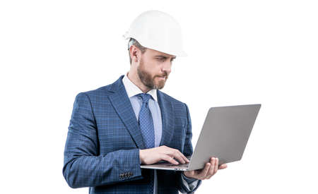 businessman man in suit and safety helmet wotking on laptop online isolated on white, work online.の写真素材