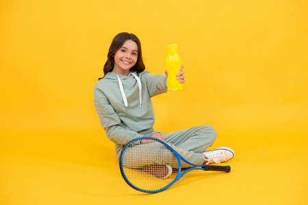 child with tennis racquet. teen girl drink water after sport training. badminton player relax.の写真素材