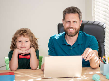 bearded dad or school private tutor teaching boy son with modern laptop, study onlineの写真素材