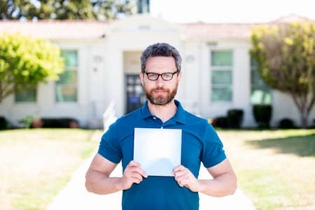 teacher man in glasses showing paper sheet, back to schoolの写真素材