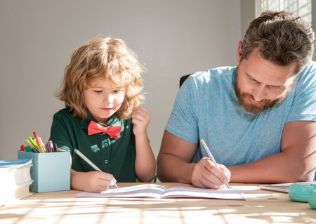 bearded father writing school homework with his kid son in classroom, educationの写真素材