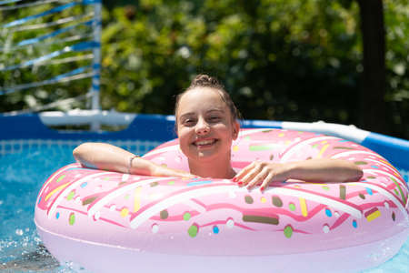 Happy kid enjoy swimming in donut pool float on sunny day, summerの写真素材