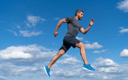 sportsman with muscular body running in sportswear outdoor on sky background, healthy lifestyle.の写真素材