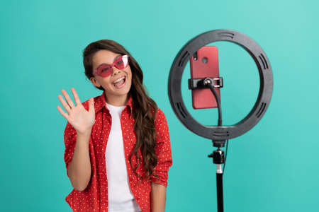 happy kid long hair waving hello on camera video blog blogging online with selfie led, vlog.の写真素材