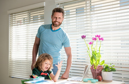 happy bearded man teacher writing school homework with his kid son in classroom, togethernessの写真素材