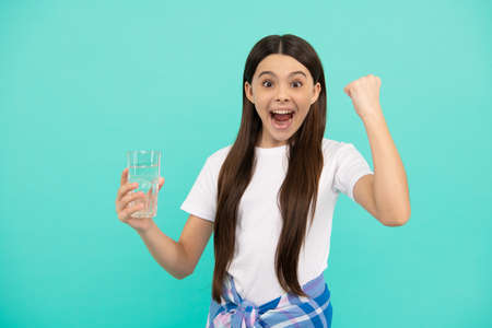 happy child going to drink glass of water to stay hydrated and keep daily water balance, health.の写真素材