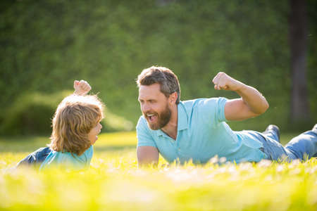 parent relax with little child boy on grass. glad dad with kid on summer day.の写真素材