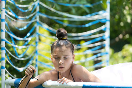 Wet girl child enjoy chilling in outdoor pool on sunny summer day, chillの写真素材