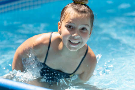 Happy wet child face portrait smiling in swimming pool on sunny summer day, girlの写真素材