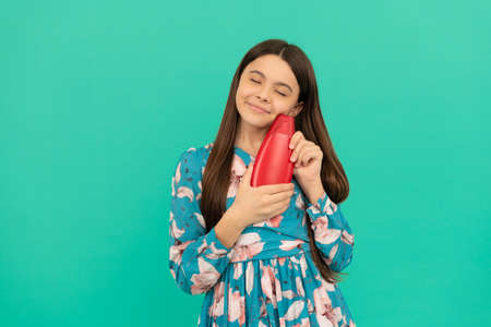 presenting cosmetic product for teen. kid with shower gel. happy girl hold shampoo bottle.の写真素材