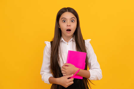 Education with fun learning. Shocked kid hold book yellow background. School educationの写真素材