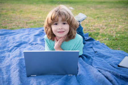Discover online learning. Boy child use laptop natural outdoors. Using learning technologyの写真素材