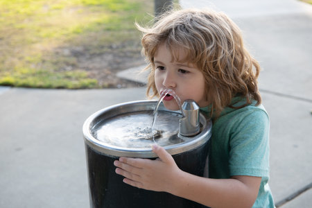Refreshment solution. Thirsty kid drink water from drinking fountain. Thirst quenchingの写真素材