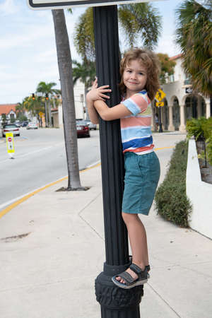 Energetic boy child climb up street lamppost summer outdoors, childhoodの写真素材