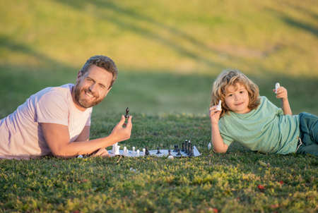 happy family of father man and son kid playing chess on green grass in park outdoor, friendshipの写真素材