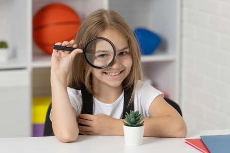 investigate with loupe. science and childhood. teen girl looking at plant through magnifierの写真素材