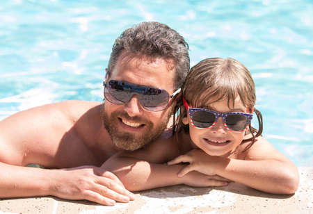 father and son wear glasses in swimming pool water. daddy with kid boy on spa resort.の写真素材