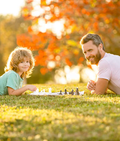 happy family of father man and son child playing chess on green grass in park outdoor, mastermindの写真素材