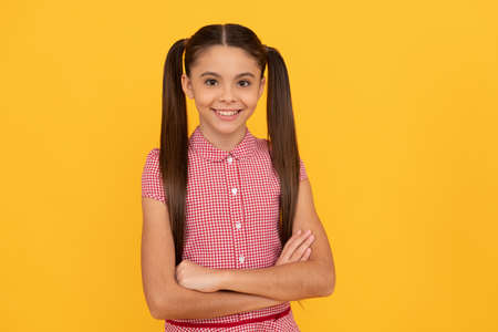 Happy confident child smile holding arms crossed yellow background, confidenceの写真素材