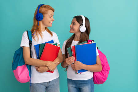 joyful private teacher and child in headphones holding copybooks and school bag, modern educationの写真素材