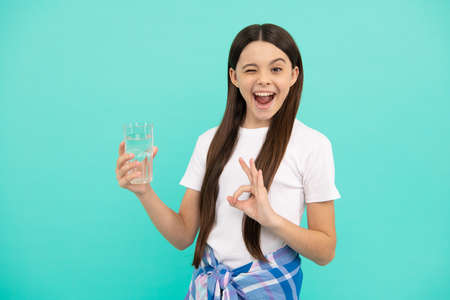 ok. kid hold glass of water. child feel thirsty. teen girl going to drink mineral beverage.の写真素材