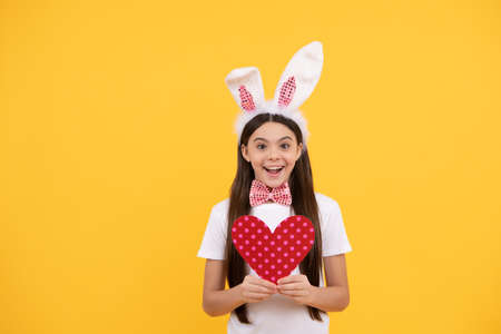cheerful bunny kid with love heart. happy easter holiday. funny child in rabbit ears. teenager girlの写真素材